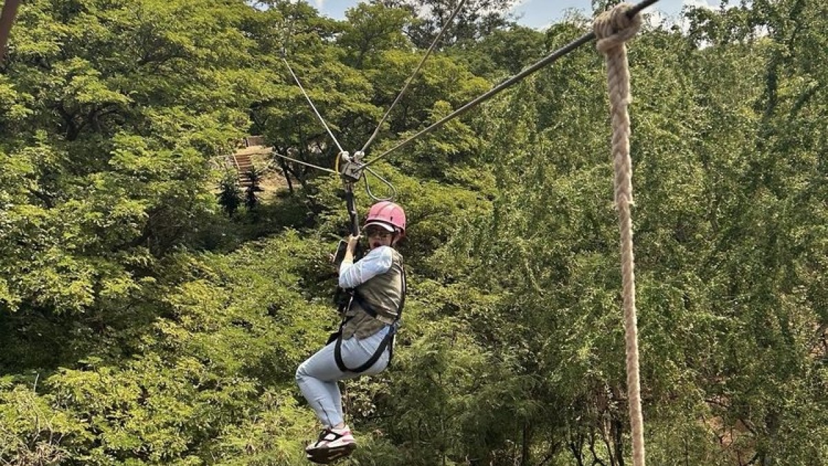 a man flying through the air while riding a swing with Skyrail Rainforest Cableway in the background