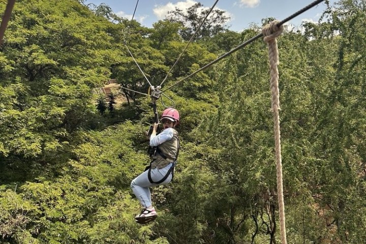 a man flying through the air while riding a swing with Skyrail Rainforest Cableway in the background