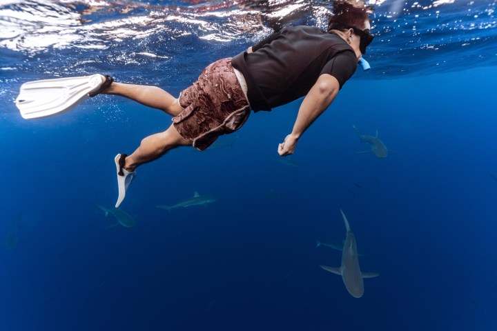 a man flying through the air while swimming in a body of water