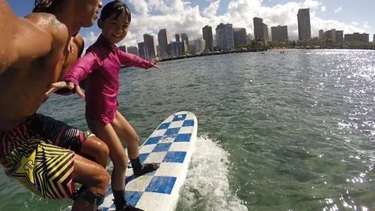 a young girl riding a wave on top of a body of water