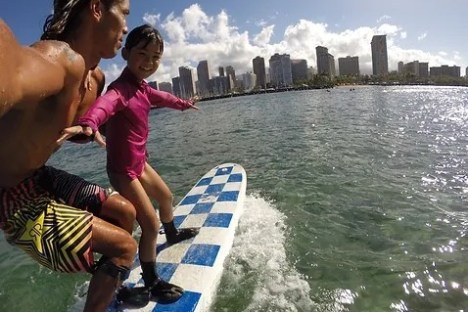 a young girl riding a wave on top of a body of water