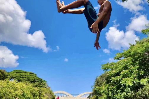 a man flying through the air while swimming in a body of water
