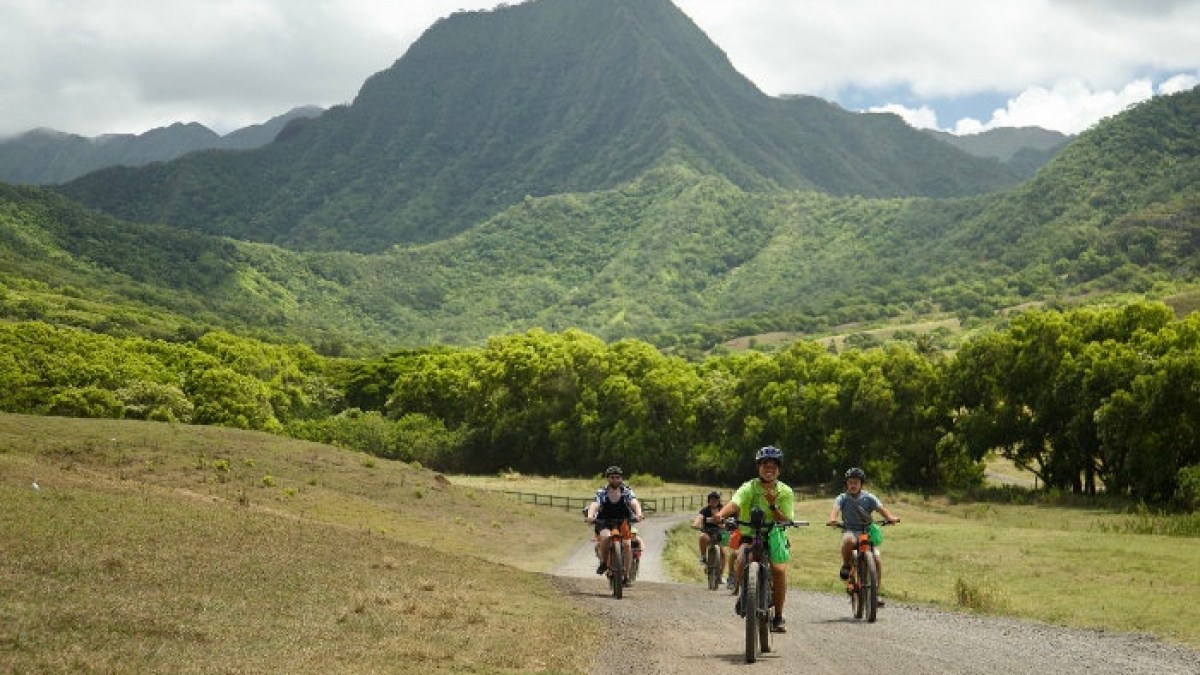 a group of people riding a motorcycle down a dirt road