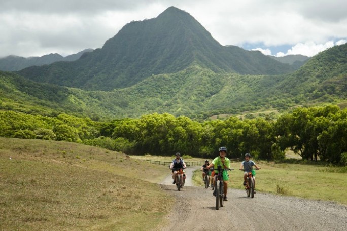 a group of people riding a motorcycle down a dirt road