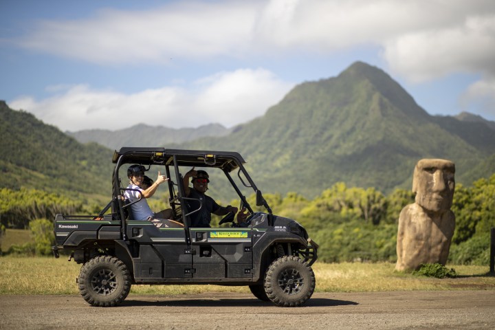 a person riding on the back of a truck driving down a dirt road