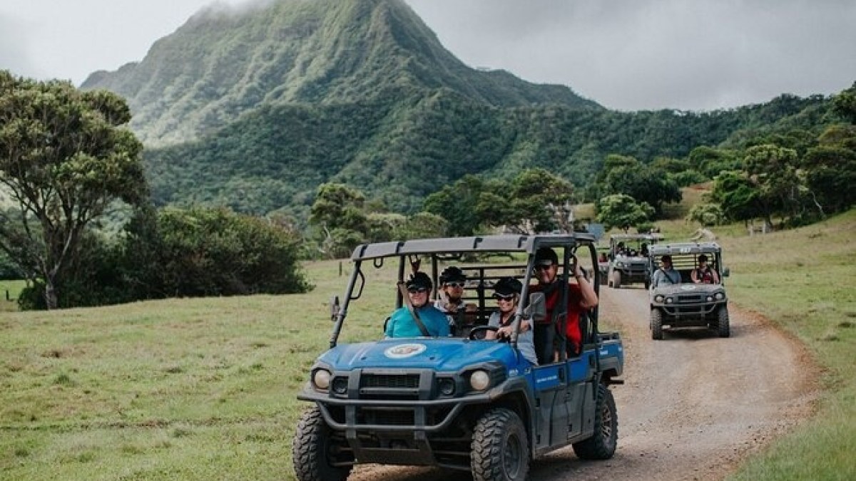 a person riding on the back of a truck driving down a dirt road