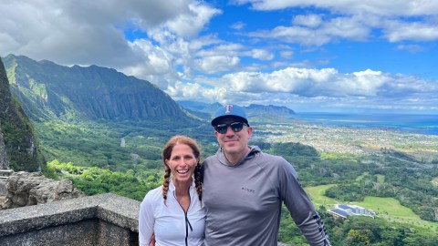 a man and a woman standing in front of a mountain
