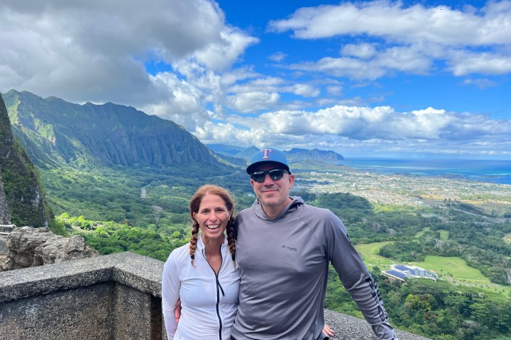 a man and a woman standing in front of a mountain