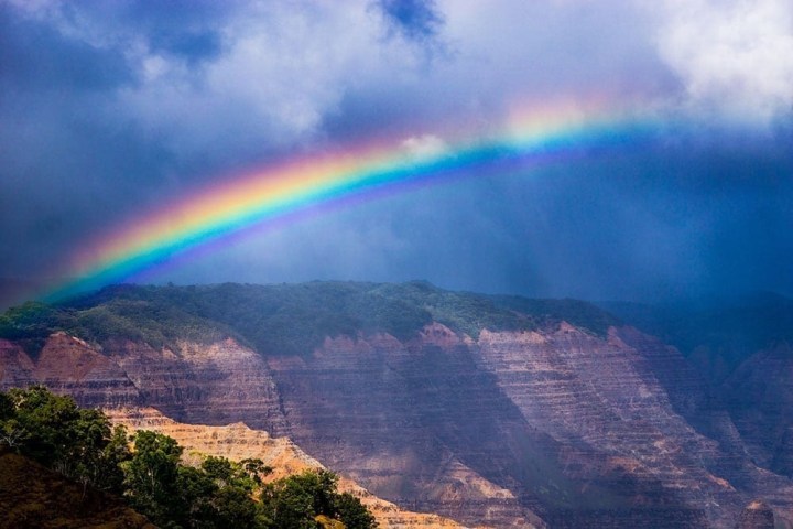 a rainbow over a body of water with a mountain in the background