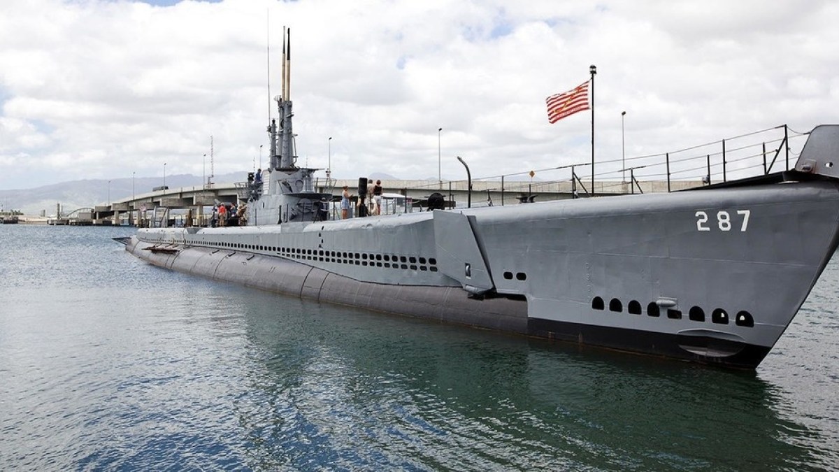 a boat is docked next to a body of water with USS Bowfin (SS-287) in the background