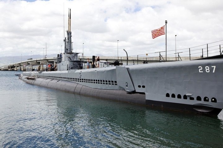 a boat is docked next to a body of water with USS Bowfin (SS-287) in the background