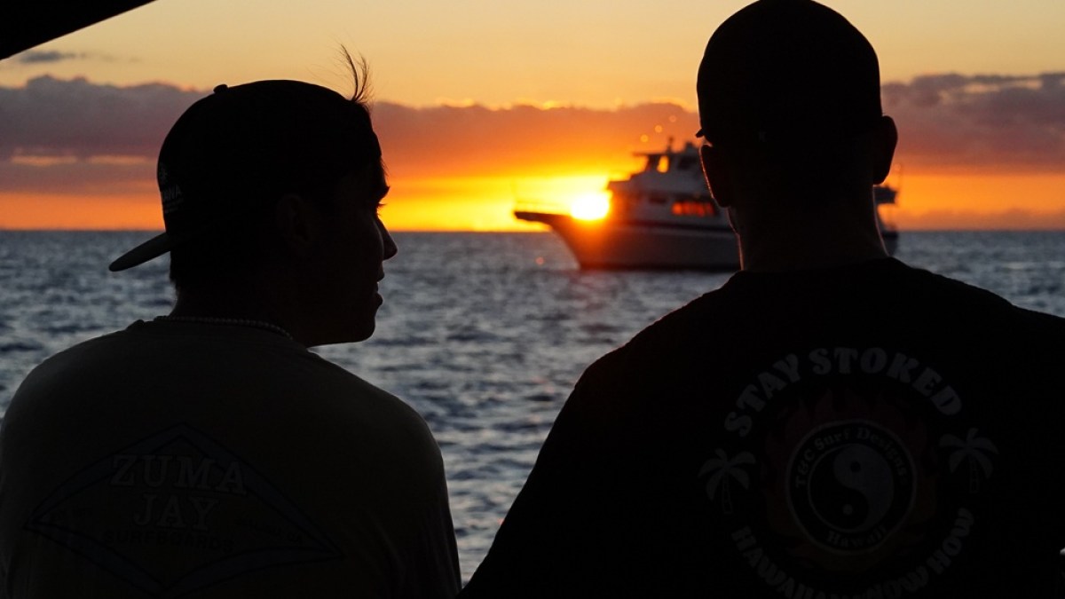 a man standing in front of a sunset over a body of water