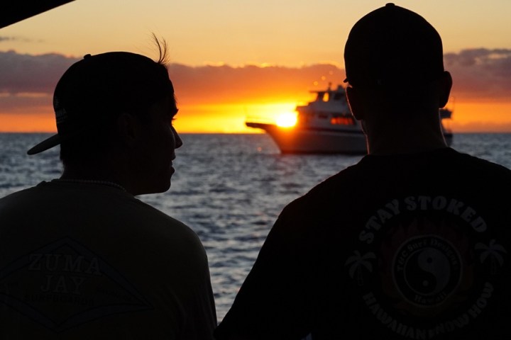 a man standing in front of a sunset over a body of water