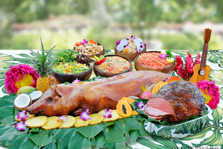 Roasted pig on tropical leaf display with fruits and bowls of food.