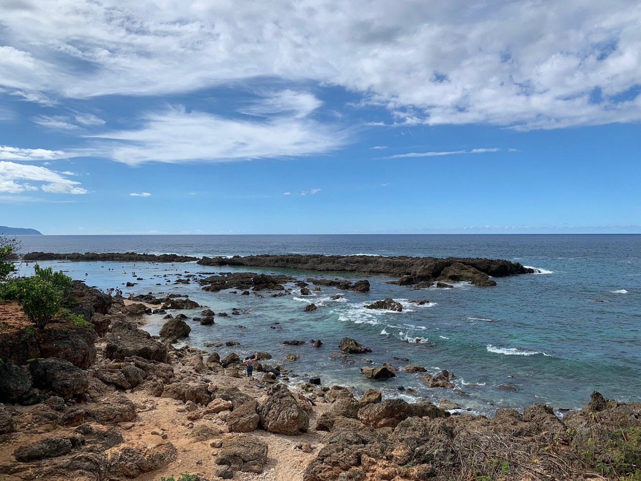 Rocky coastline with blue sky and ocean waves.